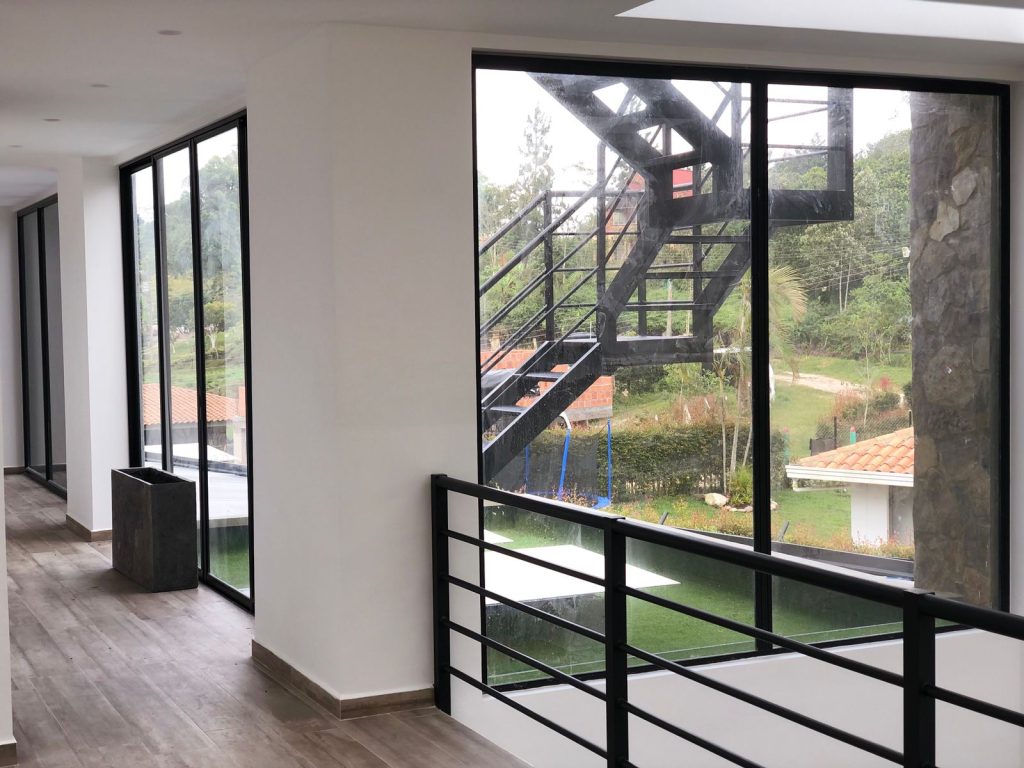 Pasillo con ventanería negra en vidrio y aluminio y baranda metálica