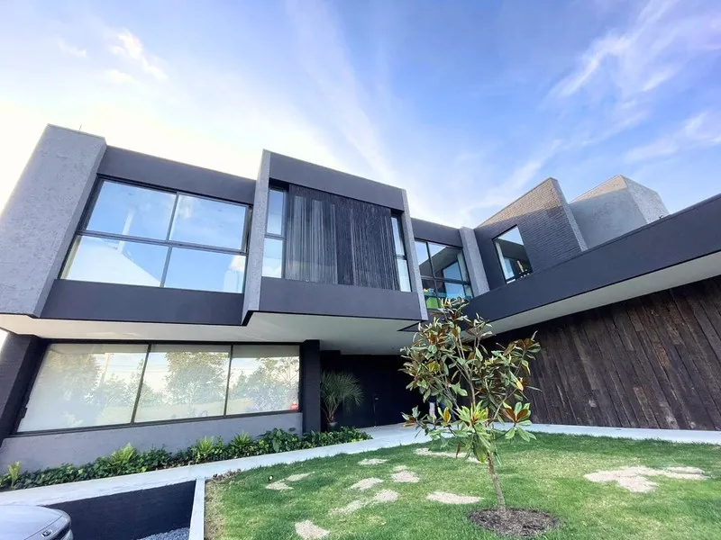Casa moderna de fachada oscura con ventanales en vidrio y aluminio