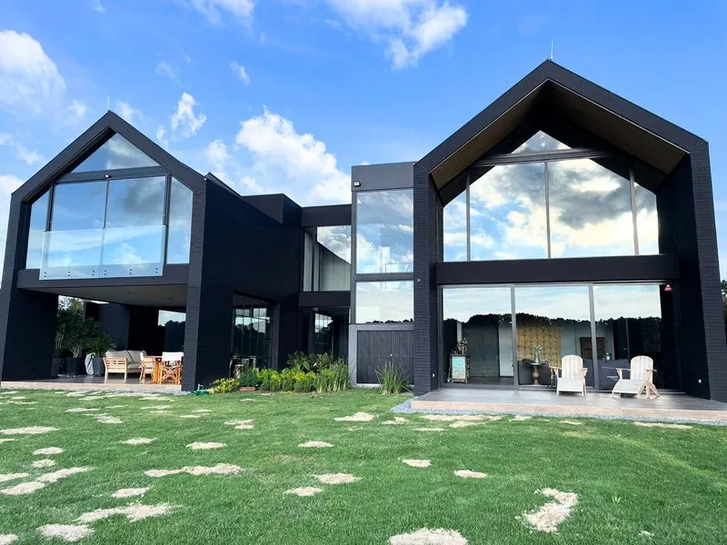 Casas de techo a dos aguas con fachadas en vidrio y aluminio negro