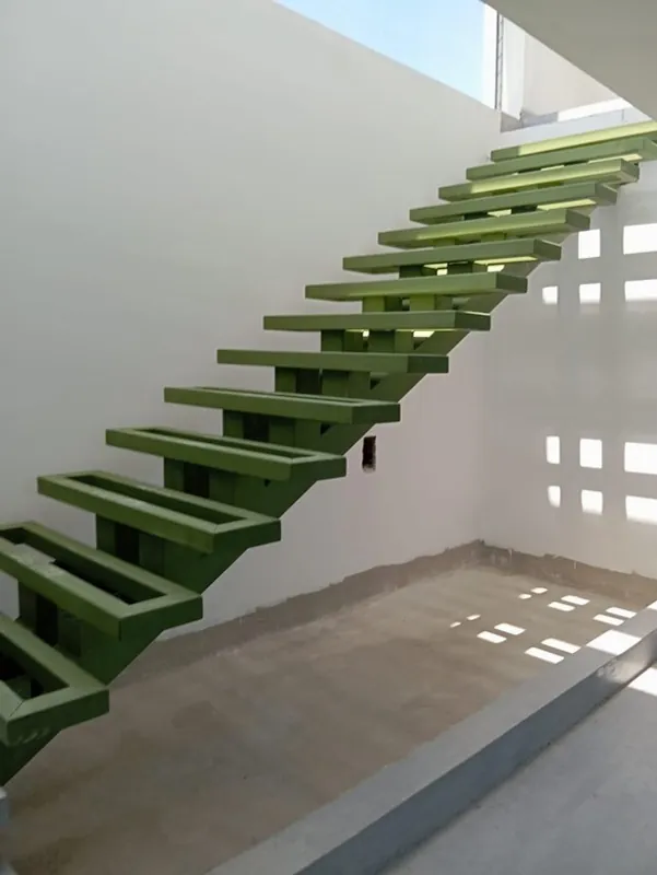 Escalera metálica de viga central instalada junto a muro con calados